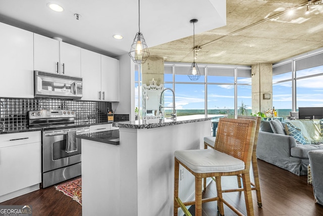 kitchen with stainless steel appliances, backsplash, a breakfast bar, and dark wood finished floors