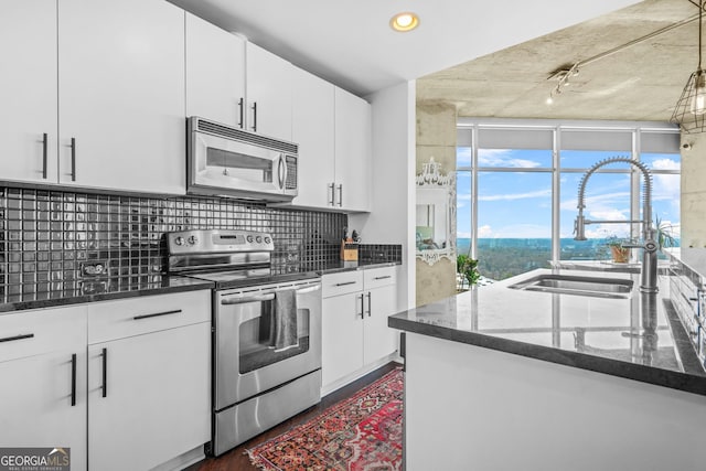 kitchen featuring dark stone countertops, backsplash, appliances with stainless steel finishes, and a sink