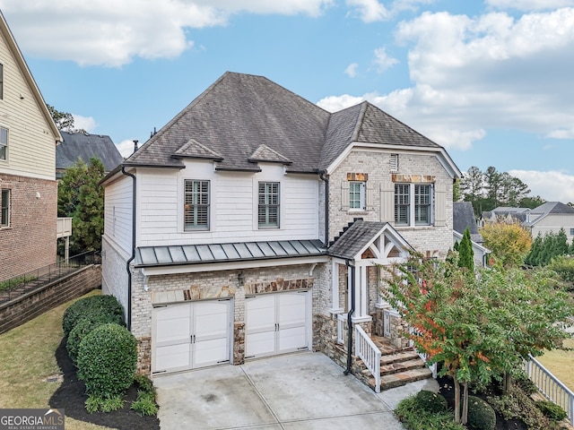 french provincial home with a shingled roof, an attached garage, a standing seam roof, metal roof, and driveway