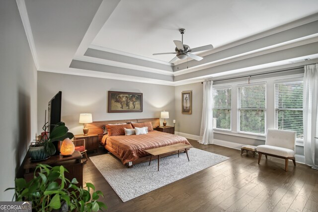 bedroom with ceiling fan, dark wood finished floors, baseboards, a raised ceiling, and crown molding