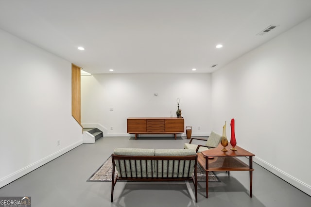 living area featuring finished concrete floors, recessed lighting, visible vents, and baseboards