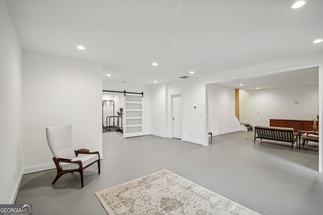 sitting room with concrete flooring, recessed lighting, and a barn door