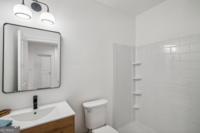 full bath with tiled shower, vanity, and toilet