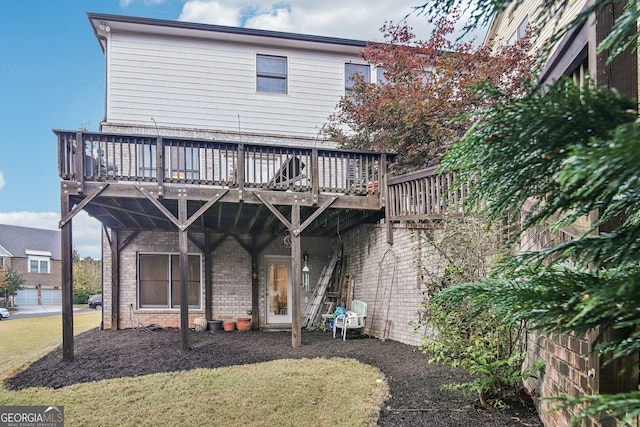 rear view of house with brick siding, a lawn, and a wooden deck