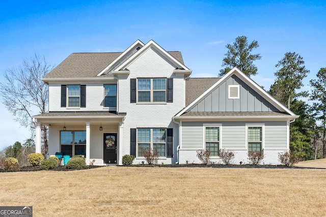 craftsman-style home with board and batten siding, a front yard, brick siding, and roof with shingles