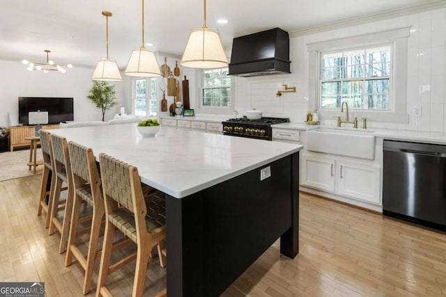 kitchen with premium range hood, a sink, black gas stove, light wood-style floors, and dishwasher