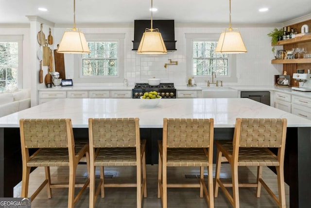 kitchen featuring ornamental molding, a sink, range, and a healthy amount of sunlight