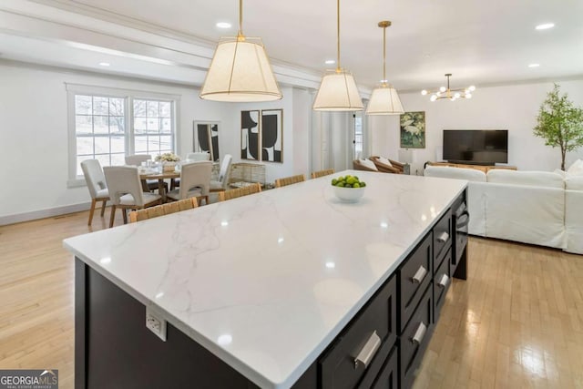 kitchen featuring a center island, hanging light fixtures, open floor plan, dark cabinets, and light wood-type flooring