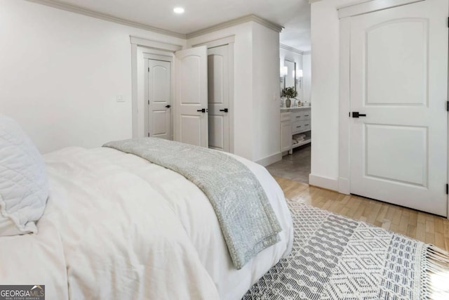 bedroom featuring crown molding, light wood finished floors, recessed lighting, connected bathroom, and baseboards