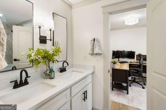 full bath with crown molding, wood finished floors, a sink, and double vanity