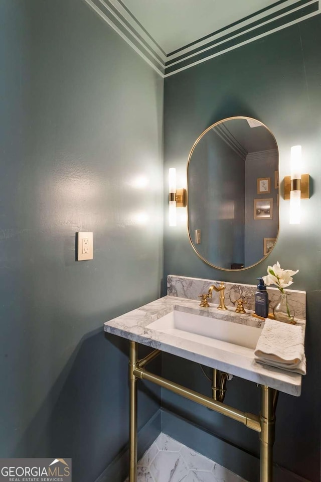 bathroom with marble finish floor, crown molding, and a sink