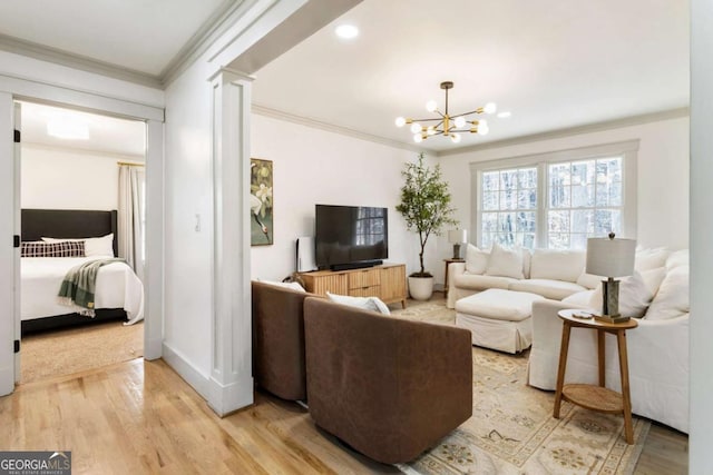 living area with decorative columns, baseboards, crown molding, light wood-type flooring, and a notable chandelier