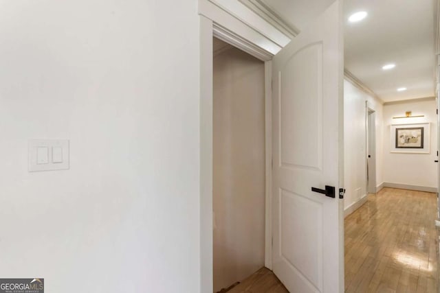 hall featuring light wood-style flooring, baseboards, and recessed lighting