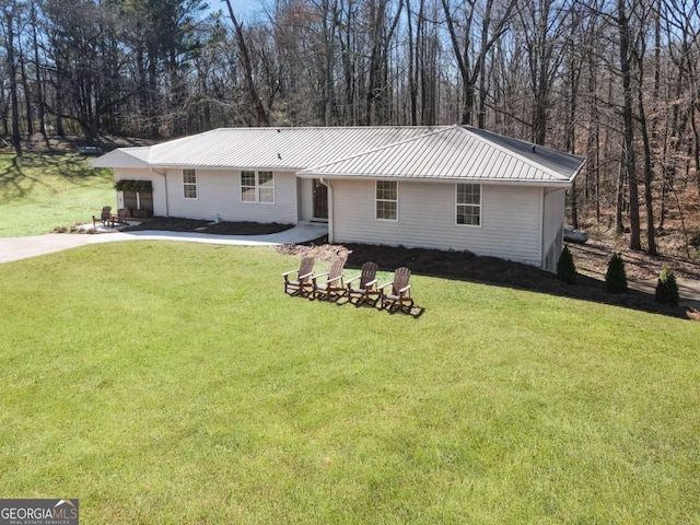 ranch-style home with metal roof, driveway, and a front lawn