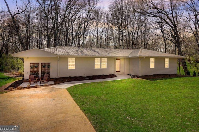 ranch-style home with metal roof, a front lawn, and a patio