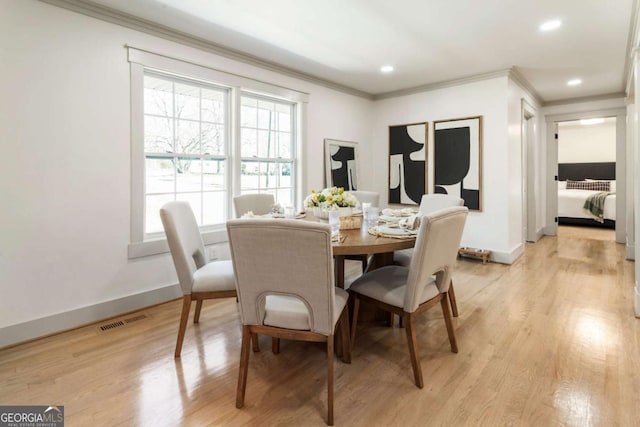 dining room featuring ornamental molding, visible vents, and light wood-style floors