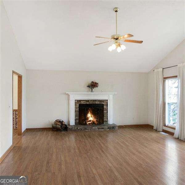 unfurnished living room with lofted ceiling, a textured ceiling, a fireplace, and wood finished floors