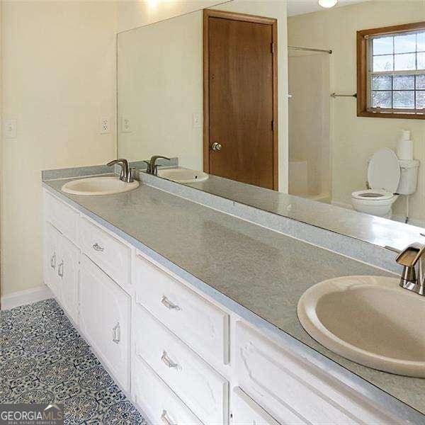 full bathroom with double vanity, walk in shower, and a sink