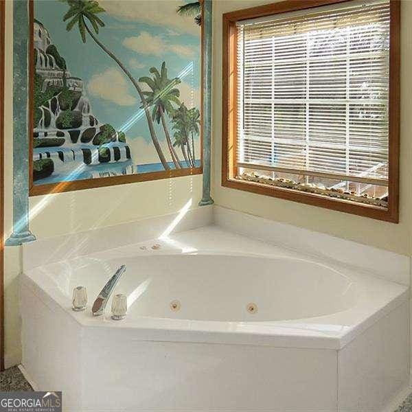 bathroom with a whirlpool tub and a healthy amount of sunlight