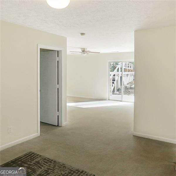 corridor with carpet, baseboards, and a textured ceiling