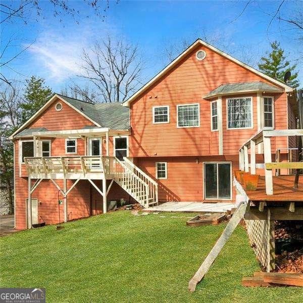 rear view of house with a deck, a patio area, a yard, and stairway