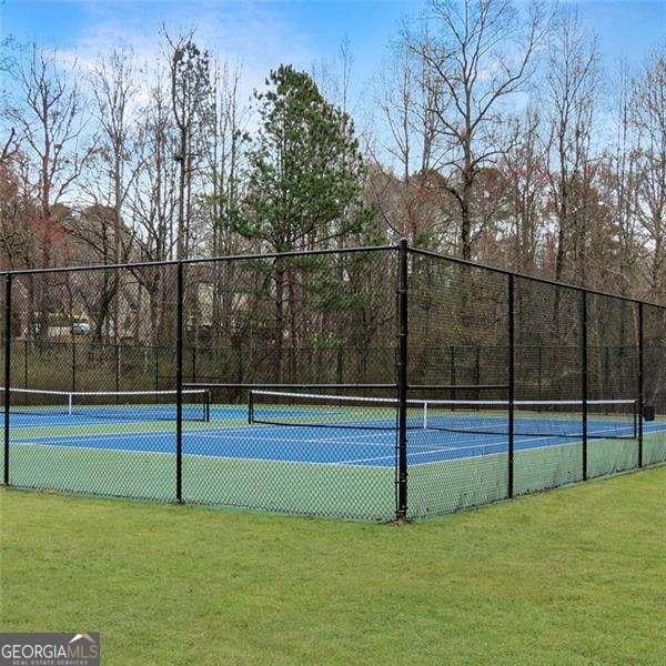 view of sport court featuring fence and a yard