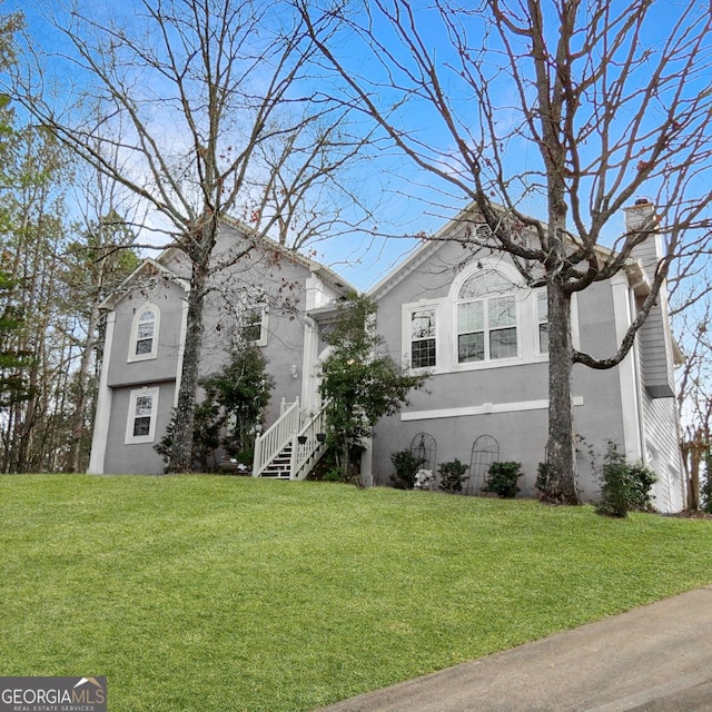 view of front of property with a chimney, a front lawn, and stucco siding