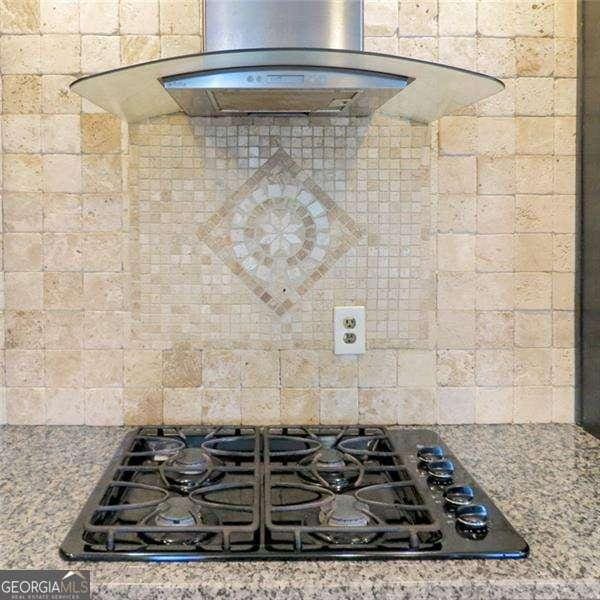 details with decorative backsplash, stone counters, black gas stovetop, and extractor fan