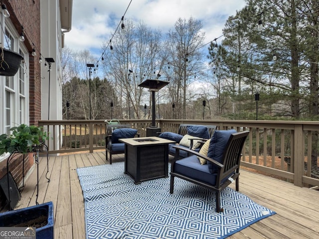 wooden terrace with an outdoor living space with a fire pit