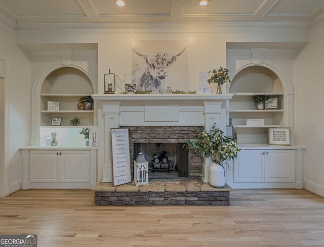unfurnished living room with built in shelves, coffered ceiling, a fireplace, ornamental molding, and light wood-style floors