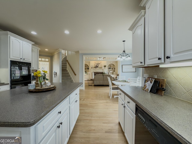 kitchen with light wood-style flooring, dark countertops, white cabinets, crown molding, and dishwasher