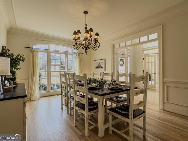 dining area featuring a decorative wall, ornamental molding, and light wood finished floors