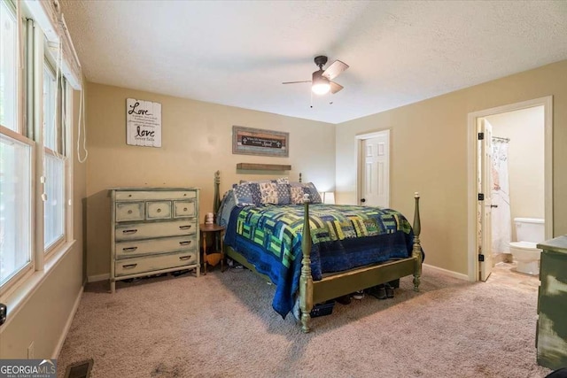 carpeted bedroom with baseboards, visible vents, ensuite bath, ceiling fan, and a textured ceiling