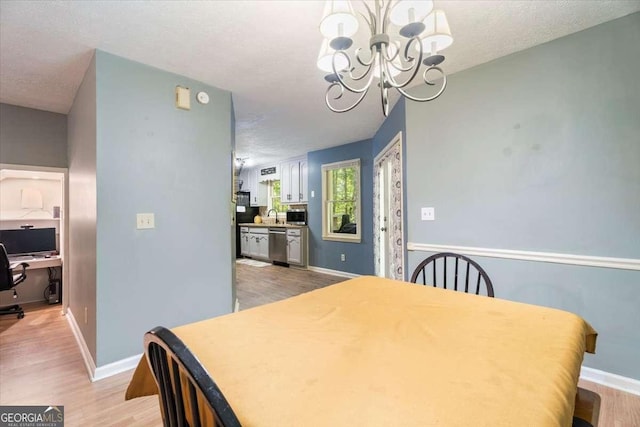 dining room featuring light wood-style floors, a textured ceiling, baseboards, and an inviting chandelier