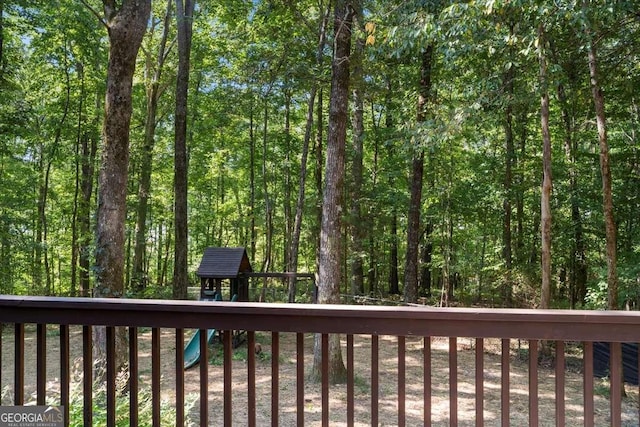 deck featuring a playground and a wooded view