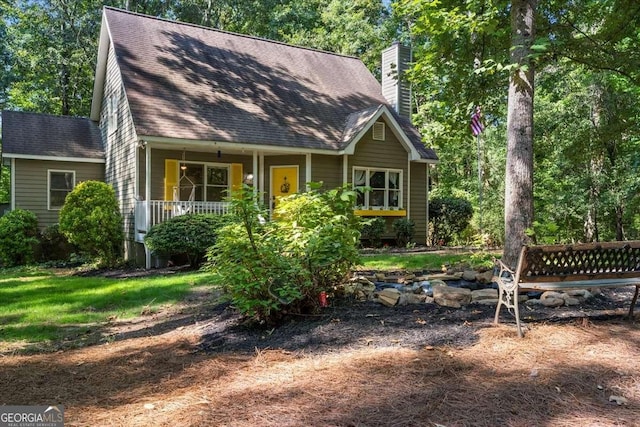 view of front of property featuring a shingled roof, covered porch, and a chimney