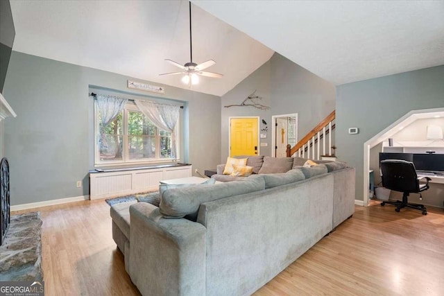 living room with radiator, light wood-style flooring, baseboards, and stairs