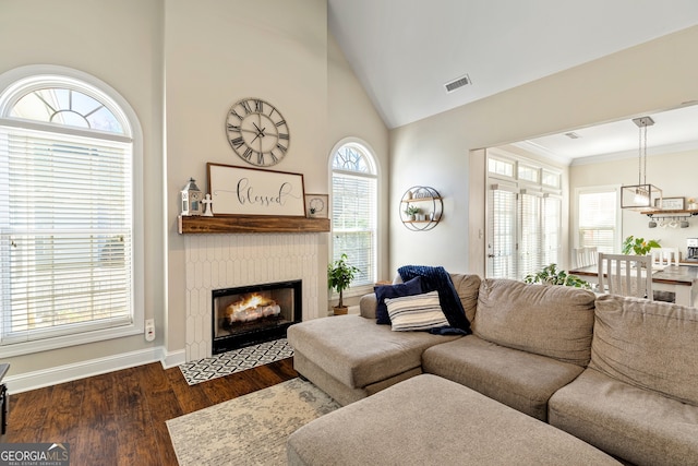 living area featuring visible vents, a fireplace with flush hearth, dark wood finished floors, crown molding, and baseboards