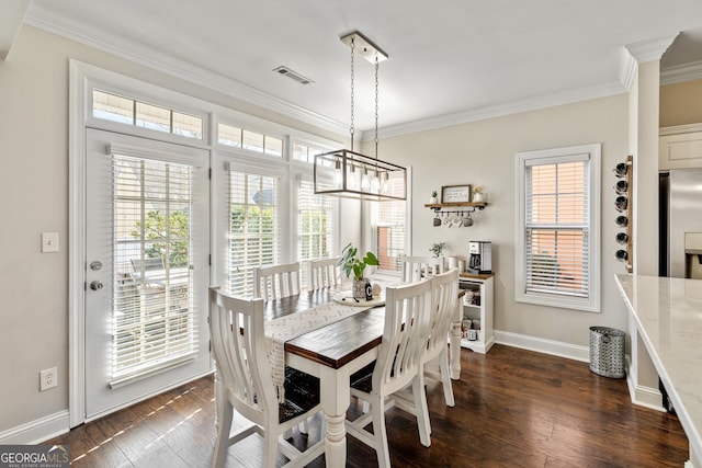 dining room with dark wood finished floors, crown molding, and baseboards