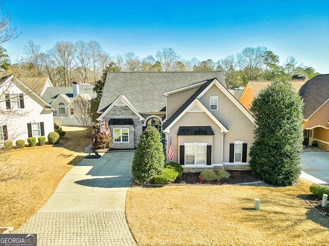 traditional-style home featuring stucco siding, stone siding, and a front yard