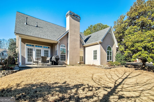 back of house featuring a patio, stucco siding, roof with shingles, and a chimney