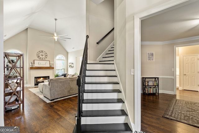 stairway featuring a glass covered fireplace, wood finished floors, and a ceiling fan