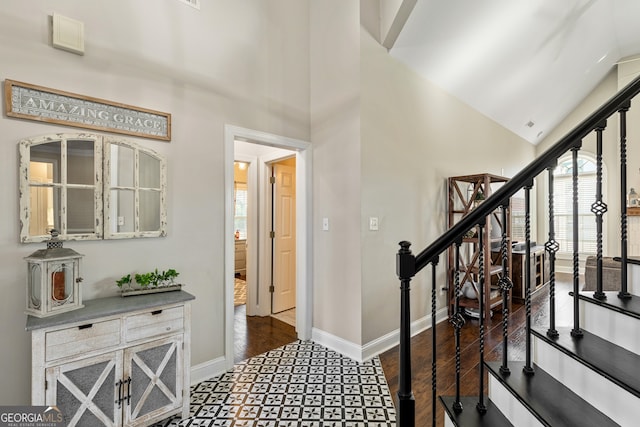 foyer featuring baseboards, high vaulted ceiling, wood finished floors, and stairs