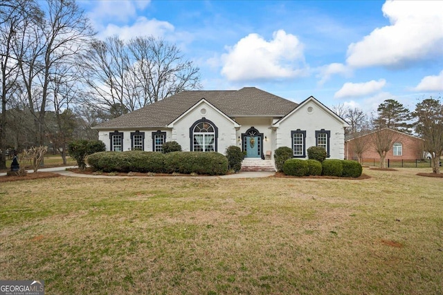 ranch-style home with a front lawn and fence