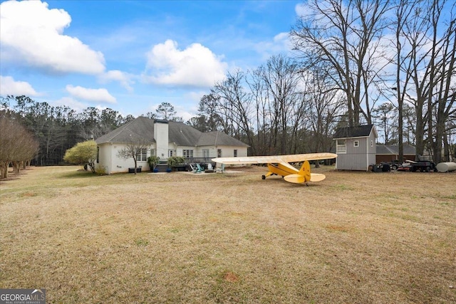 back of house with a storage unit, a lawn, and an outdoor structure