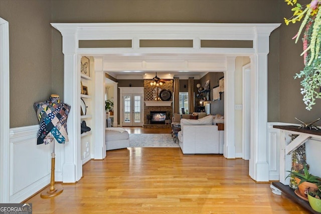 interior space featuring light wood-type flooring, a glass covered fireplace, a ceiling fan, and built in features