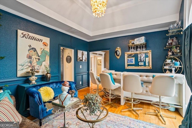 bar featuring a notable chandelier, a dry bar, a raised ceiling, ornamental molding, and wood finished floors