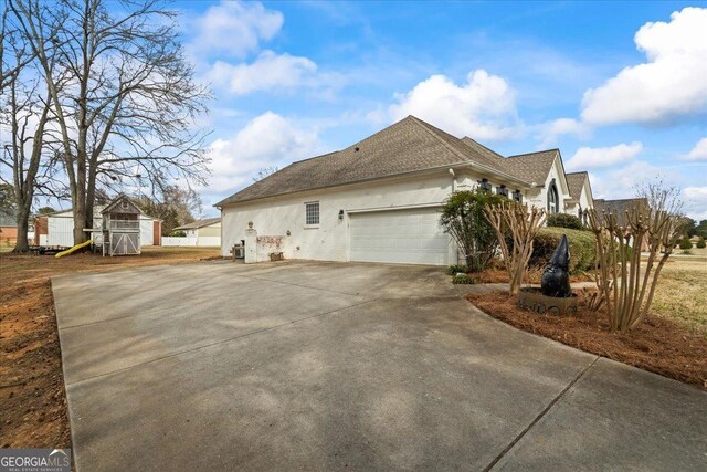 3403 Bill Gardner Pkwy, Locust Grove, GA 30248 - view of side of home with stucco siding, concrete driveway, a garage, and roof with shingles