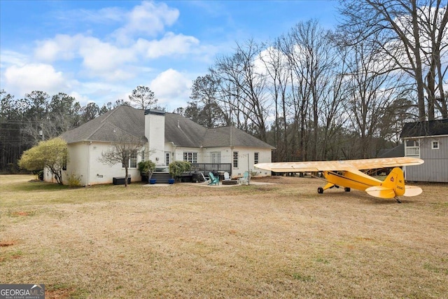 back of house featuring a deck, a lawn, and a chimney