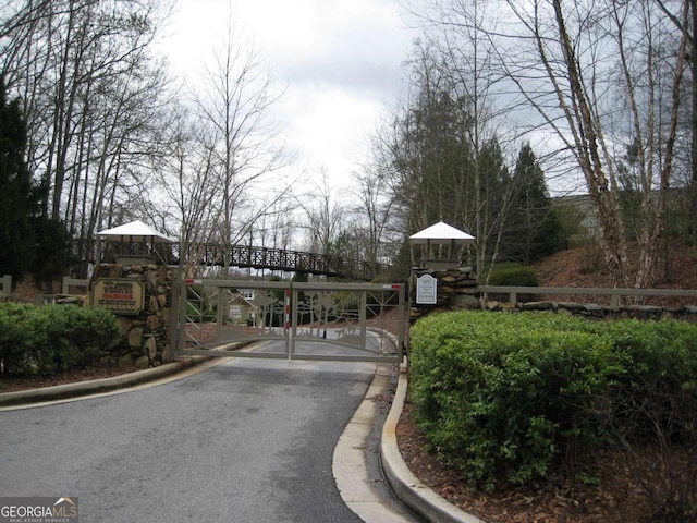 view of street with a gate, curbs, and a gated entry